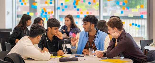 A group of male and female students sat at a table discussing a project